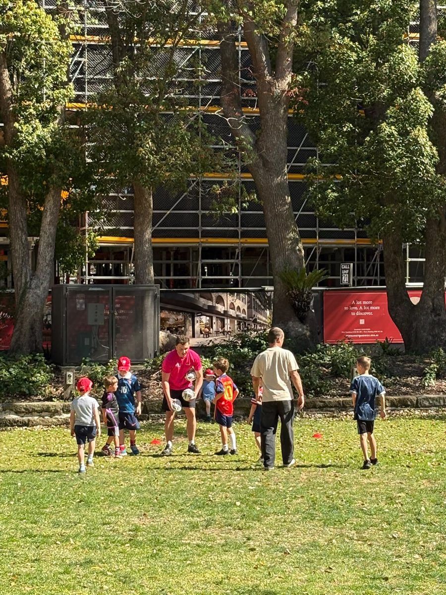 Coach Jo running games with a group of young kids at Queens Park